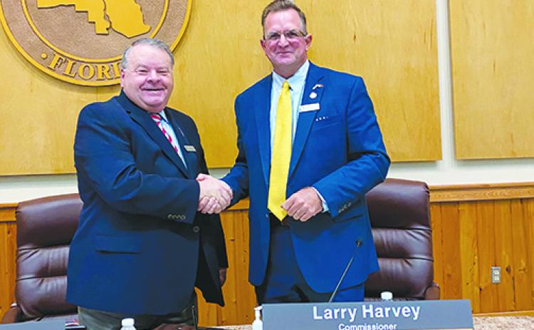 Previous and current Board of County Commissioners chairmen Terry Turner and Larry Harvey shake hands after the transition. 