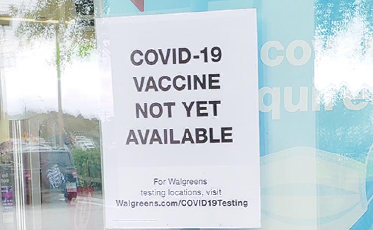 Signs on the door of Walgreens in Palatka show COVID-19 vaccines are not yet available to the public. 