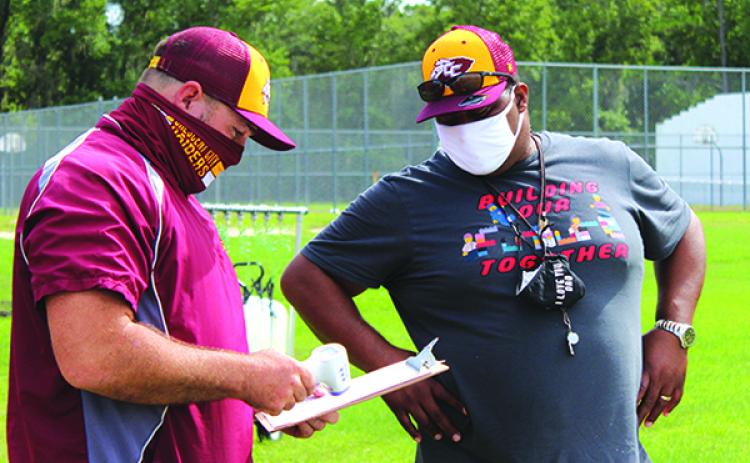 Stacy Cook, right, goes over COVID-19 protocols with athletic director and fellow Crescent City High School assistant football coach Tim Ross on the first day of practice in August. (MARK BLUMENTHAL / Palatka Daily News)
