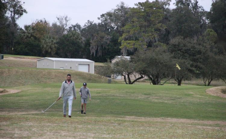 Mike Meredith and his son, Luke, walk the greens at the Palatka Municipal Golf Course during the late afternoon on Tuesday. (MARK BLUMENTHAL / Palatka Daily News)