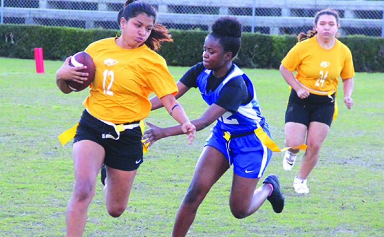 Crescent City’s Isabella Torres (12) looks to avoid the flag-pull attempt of Palatka’s Samaria Williams. Crescent City’s Jasmine Vidana is in the background. (ANTHONY RICHARDS / Palatka Daily News)