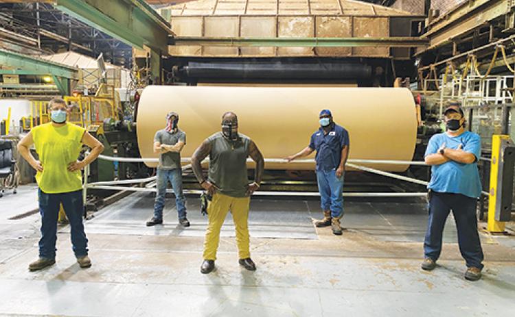 Georgia-Pacific employees stand in front of a kraft paper machine, which produces the paper for Amazon’s recyclable envelopes, a service the Palatka plant’s manager said has cemented the company even deeper in Putnam County.