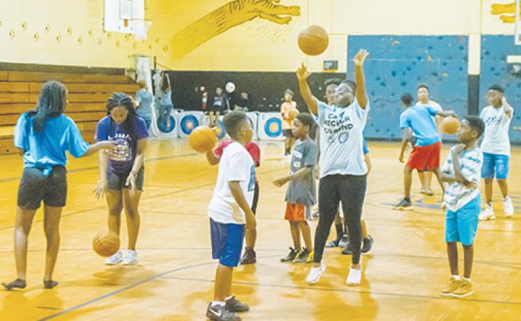 Counselor Zaria Long, center, shows some of the campers her basketball moves as they play basketball together at Camp Higher Ground in 2019 as part of the Palatka Police Department’s Police Athletic League.