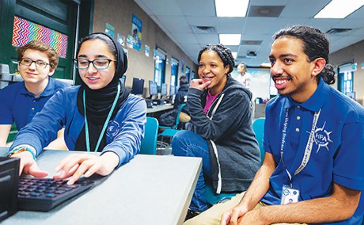 Students and a Microsoft employee work together through the company’s Technology Education and Literacy in Schools program.