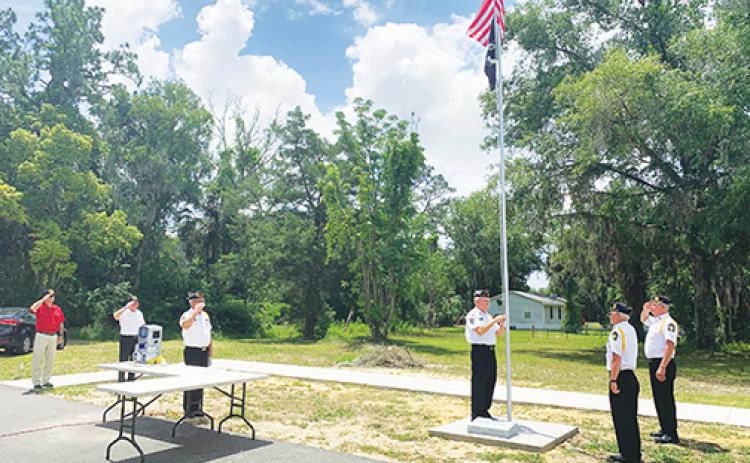 A crowd of about 20 people attend the ceremony honoring the flag and flagpole at Veterans Village on Thursday.