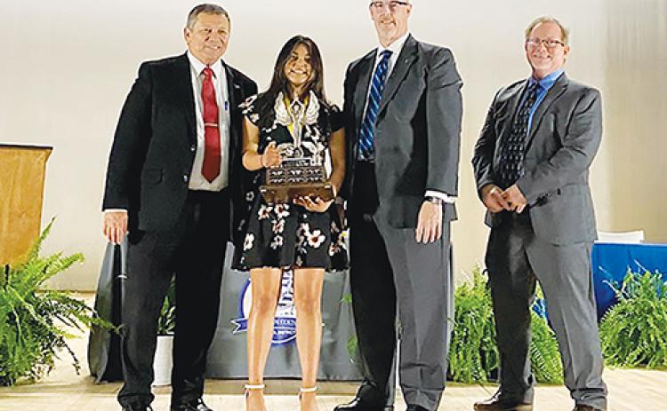 Robert W. Webb Award of Excellence winner Lizbeth Espinoza holds her award at the Putnam County School District’s Top Scholars ceremony Thursday night. From left, Superintendent Rick Surrency, Robert Webb’s son, Doug Webb, and Palatka Daily News Editor Wayne Smith join Espinoza.