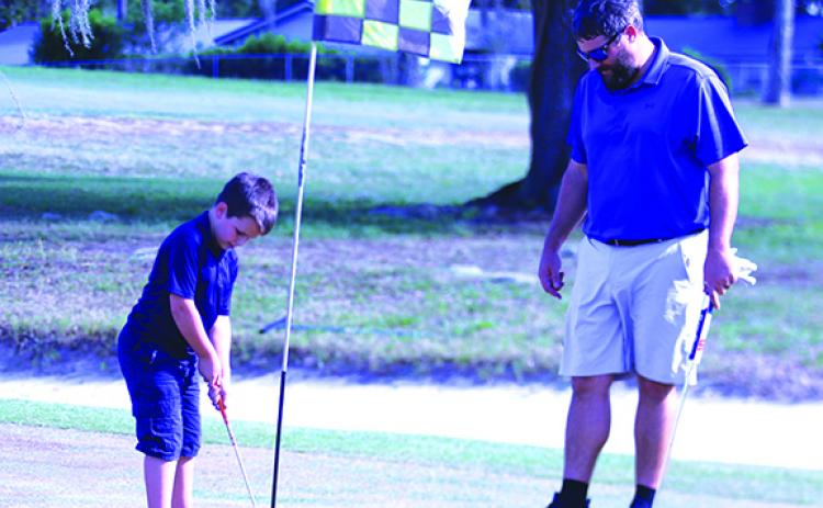 Jeff Malandrucco, right, watches his son Jackson, 6, putt on the 18th green during father-son play at Palatka Muncipal Golf Club on Tuesday. (ANTHONY RICHARDS / Palatka Daily News)