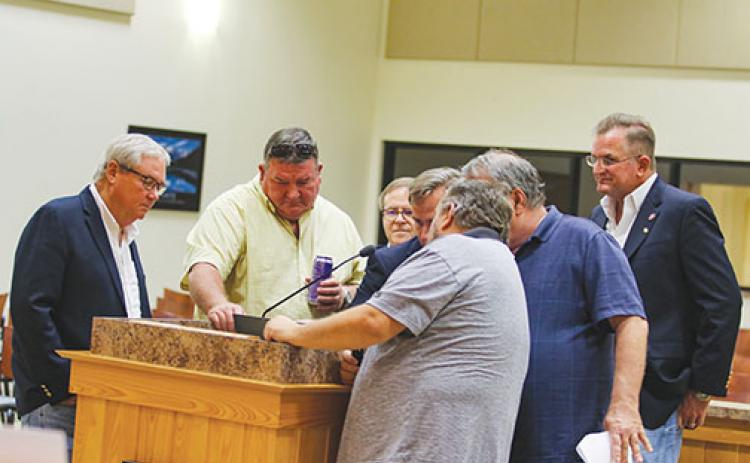 County commissioners gather around a map of local voting districts Tuesday as they rework the area’s five districts.
