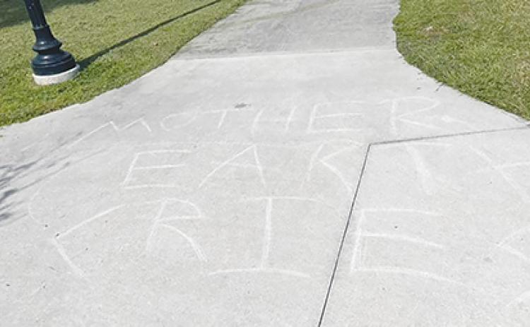 The words “Mother Earth cries” are written on a sidewalk in downtown Palatka.