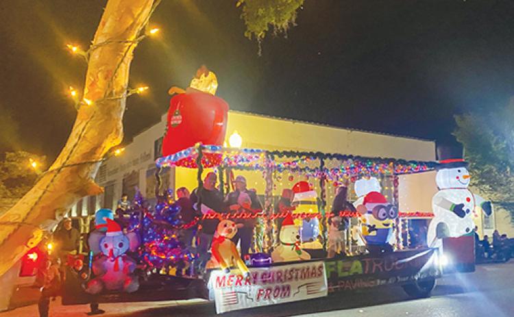 People representing FLA Trucking & Paving get into the holiday spirit Friday as they ride down St. Johns Avenue during the Palatka Christmas Parade, which returned this year after being canceled in 2020 because of COVID.