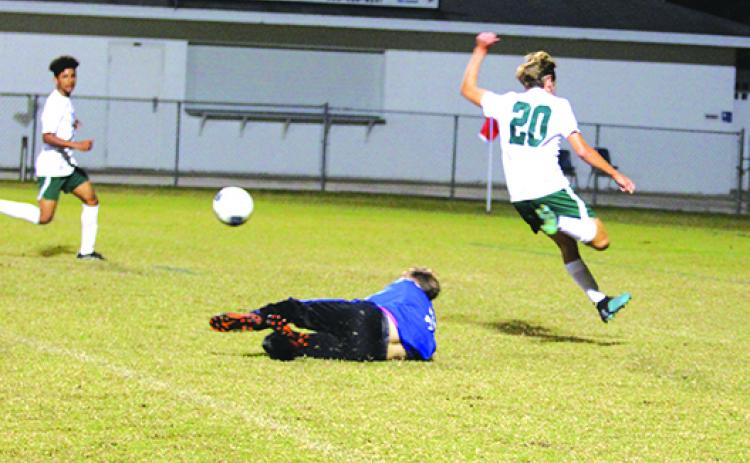 Palatka High School goalkeeper Braeden Brauman dives to make a stop of a shot with Flagler Palm Coast’s Chase Magee (20) jumping over him during the first half. (MARK BLUMENTHAL / Palatka Daily News)