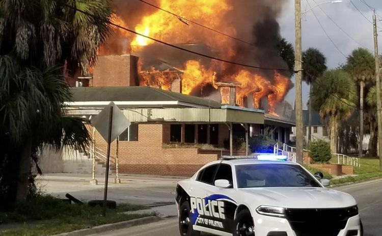 A Palatka Police Department vehicle sits Sunday in front of the former Florida Furniture factory on River Street as flames pour from the windows. Courtesy of Steph Bollerud.