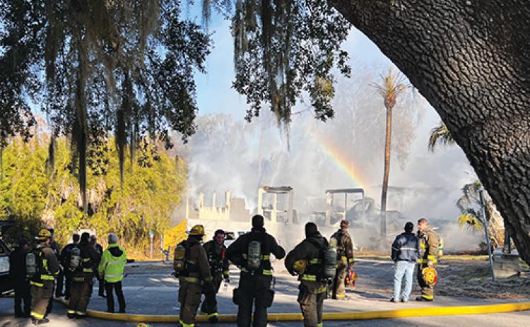 Firefighters stand in front of a burnt building in Welaka after dousing the flames Monday.