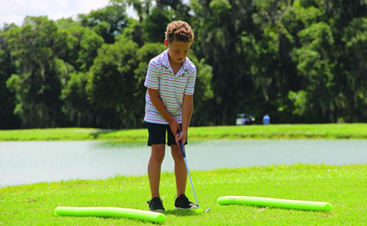 Seven-year old Lennox Harper works on his chipping skills Tuesday during the golf clinic at Palatka Golf Club. (COREY DAVIS/ Palatka Daily News)