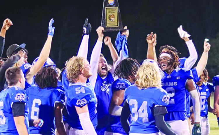 Interlachen Junior-Senior High School football coach Erik Gibson (center) hoists the Sunshine State Athletic Conference Atlantic Division championship trophy after his Rams took down Jacksonville Paxon, 16-0, on Nov. 4 and finished the season at 10-0. (RITA FULLERTON / Special to the Daily News)