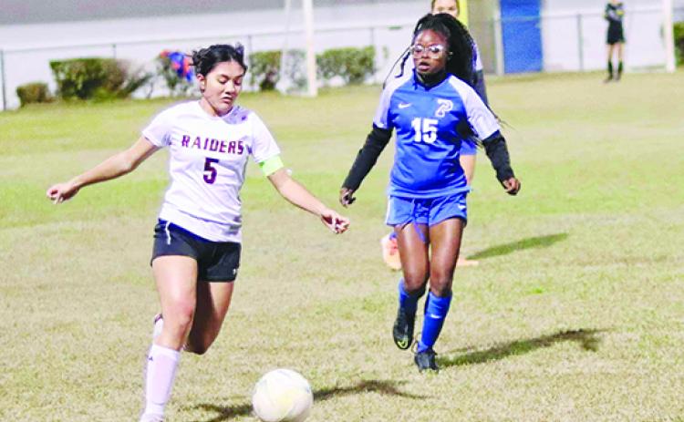 Crescent City’s Maylin Vaillancourt moves the ball up the field as Palatka’s Ymira Passmore chases her down during the first half of Friday night’s game at Bennett-Cooper Field at Veterans Memorial Stadium. The Raiders won the game, 1-0. (RITA FULLERTON / Special to the Daily News)