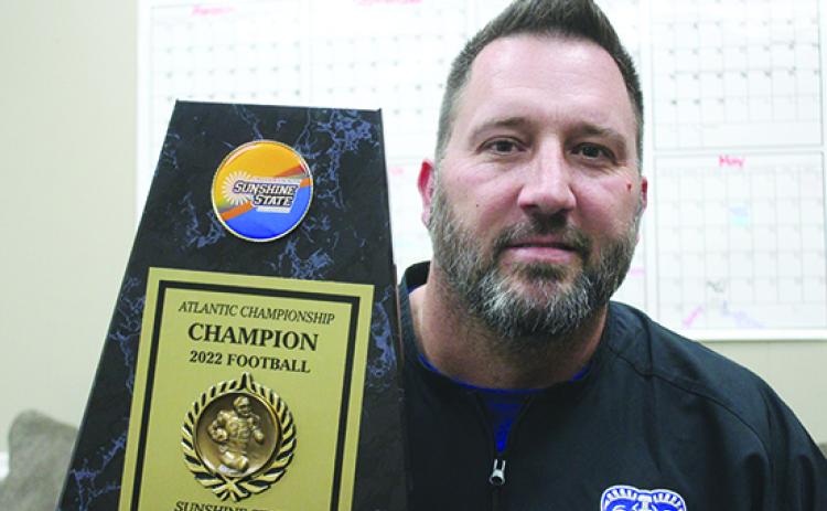 Interlachen Junior-Senior High football coach Erik Gibson poses with the Sunshine State Athletic Conference Atlantic Division Tournament trophy his team won in November to finish a 10-0 season. (MARK BLUMENTHAL / Palatka Daily News)