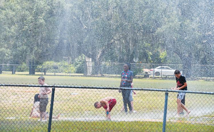Children in Interlachen beat the heat as a firetruck sprays water over them at one of the town’s baseball fields during the town’s Fourth of July celebration.