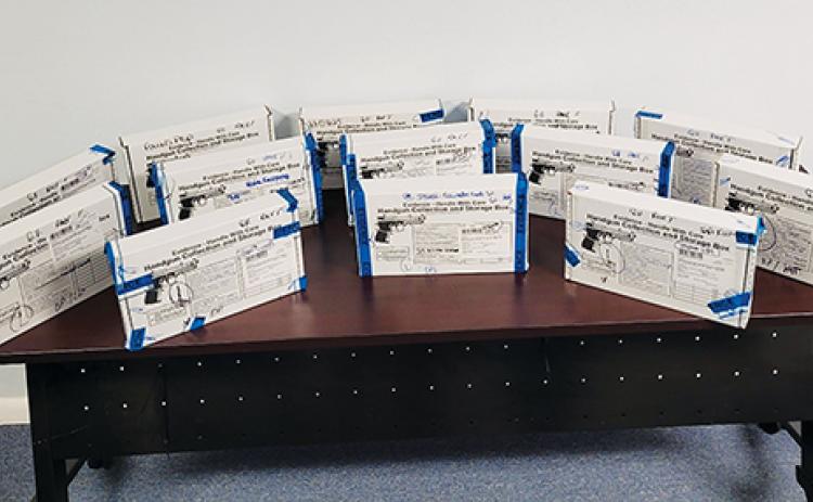 Photo courtesy of the Palatka Police Department – Thirteen of the 44 firearms seized by the Palatka Police Department are displayed in evidence boxes on a table at the police department.