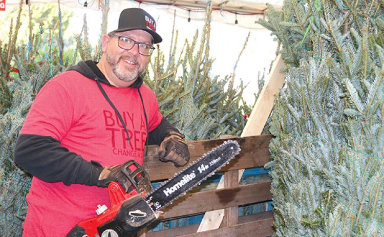 TRISHA MURPHY/Palatka Daily News – Steve Burkowske, the site director for Buy A Tree Change A Life – Palatka, gets ready to trim a Christmas tree that will be for sale at Open Door Church of God, 3704 Crill Ave. in Palatka.