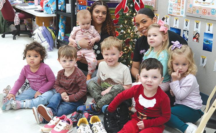 TRISHA MURPHY/Palatka Daily News – Joannie Millan, back right, and her daughter, Jileyshka Rodriguez, 17, back left, sit with some of the children in the One in a Mellon Learning Center daycare with donated shoes that will be given to students in need. 