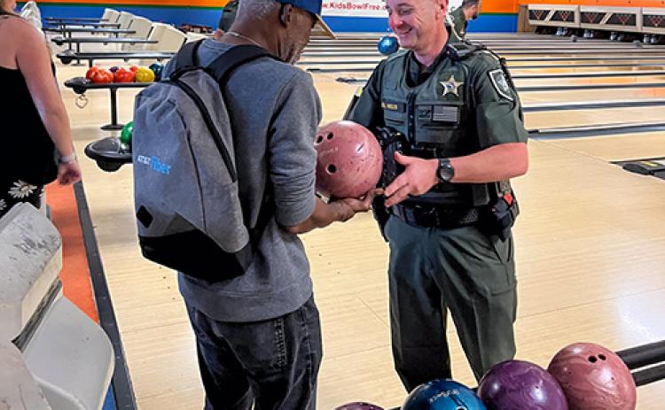 Photo submitted by Lisa Taliaferro. Putnam County Sheriff's Office Col. Joe Wells works with a man Friday to show him how to bowl during Patients Not Prisoners bowling event.