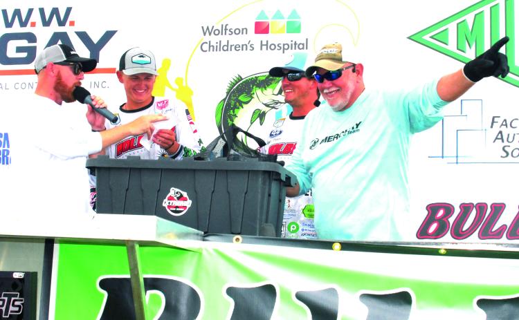 Tournament co-emcee Paul Hamilton makes the hand-raised call of winning weight 28.29 pounds for Parker Stalvey (second, left) and Syler Prince (second, right) at Saturday’s Wolfson Children’s Hospital bass tournament. At left is co-emcee Brian Stahl. (GREG WALKER / Daily News correspondent)