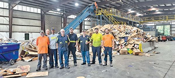 File photo – Employees of the Raleigh County Solid Waste Authority in Beckley, West Virginia, stand in front of the recyclables that pass through the facility.