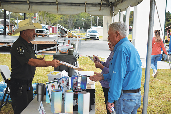 BRANDON D. OLIVER/Palatka Daily News – Putnam County Sheriff’s Office Lt. Steven Breckenridge gets people signed up for a drawing to win a cooler during the Ten-24 Foundation fundraiser Friday evening.