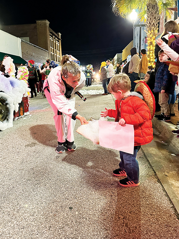 Photo submitted by Allison Waters-Merritt – An official from Pak’s Karate in Palatka hands a child a collection of artificial snow Friday evening during the parade.