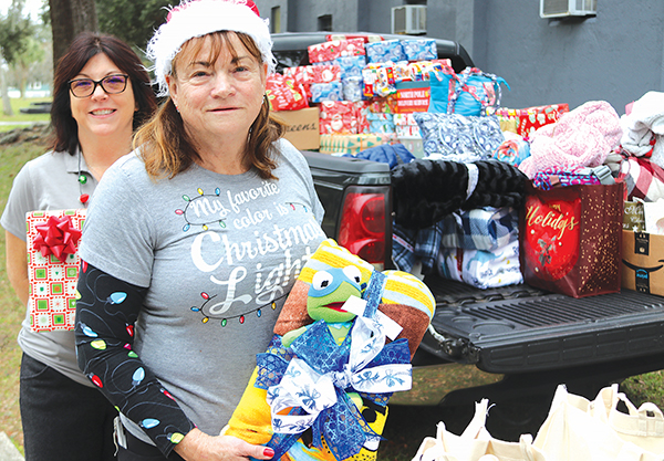 TRISHA MURPHY/Palatka Daily News – Bread of Life Kitchen Manager Theresa Odom, front, and board member Leota Wilkinson stand in front of a truckload of donated gifts that were given away Friday to Bread of Life neighbors. 