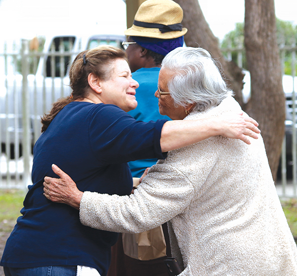 TRISHA MURPHY/Palatka Daily News – Bread of Life volunteer Holly Monroe, left, hugs a neighbor who stopped by the soup kitchen Friday as volunteers handed out food and gifts.