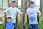 Justin Atkinson, left, and Brett Bollinger hold up their winning fish on Saturday. Conner Atkinson, Justin’s son, joins in the festivities. (GREG WALKER / Special To The Daily News)