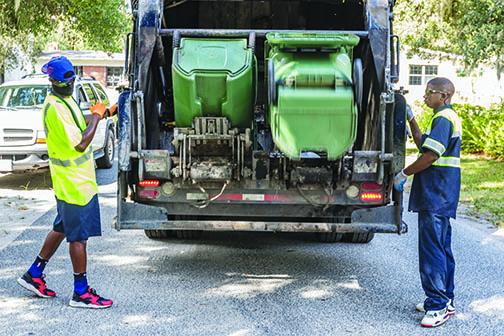 Palatka sanitation workers load trash into the truck Tuesday morning.