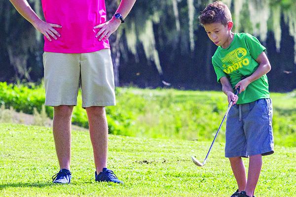 Under the watchful eye of instructor Troy Sheffield, eight-year-old Ely Watson tries his hand at a golf clinic last summer. The City of Palatka Recreation Department is holding six weeks of beginner youth golf lessons. For details, call 983-1254. (Daily News file photo)