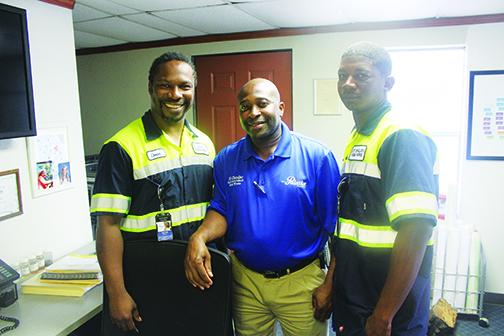 Palatka Public Works employees Tremain Watts, left, and Deon Fells, right, are congratulated by their supervisor Ed Chandler.