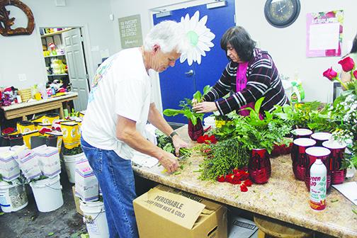 Flowers by Melanie employees Gary Nilsson and Jill Stephens trim the stems off roses Monday afternoon to prepare for Valentine’s Day.