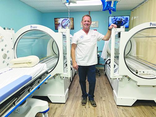 Hyperbaric Specialist Mitchell Hall stands in front of oxygen beds at the grand opening of Hyperbaric Health Services.