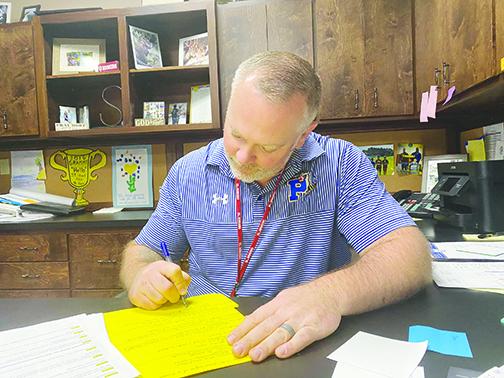 Palatka High School Principal J.T. Stout finishes paperwork Friday as the he confirmed the cancellation of several school field trips due to coronavirus.