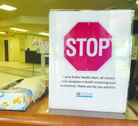 A sign at Putnam Community Medical Center informs employees and visitors the hospital requires coronavirus screenings for people who enter.