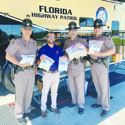 A Hagan Ace Hardware official presents hand sanitizer and bug spray that store employees donated to Florida Highway Patrol troopers Wednesday.