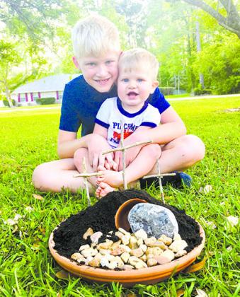 Truett Duke, 8, and his brother, Hudson, 14 months, are pictured with the Resurrection Garden the family puts together every Easter.