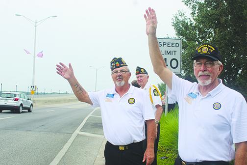 American Legion Bert Hodge Post 45 Commander Ken Moore and member Bo Meadows wave to cars Monday to honor people who have served in the military.