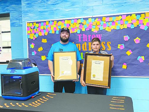 Ochwilla Elementary School robotics coach Brian Parrish and Interlachen Elementary School student Brian Bunch accept proclamations Wednesday for making face mask straps. 