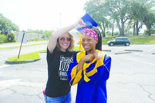 Becci Motes, Palatka High School’s Jobs for Florida Graduates specialist, gives PHS senior Diovoinne Fells her cap and gown.