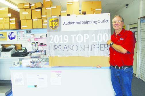 City Shippers owner Greg Bacon displays the banner he got from UPS for being one of the top 100 shipping partners in the country.