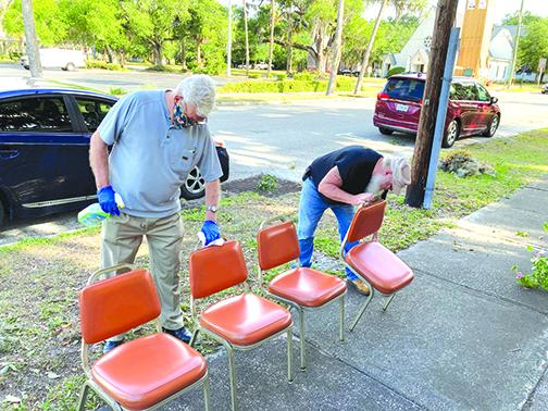 Ronnie Beams and Michael Burkhart of Liberty Baptist cleans chairs they took out of the church following the building being tented for termites.