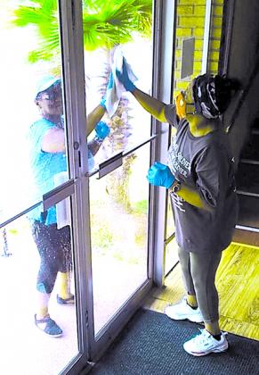 Mary Thomas and Diana Ware of Calvary Missionary Baptist Church clean the doors at the entrance of the Palatka church.