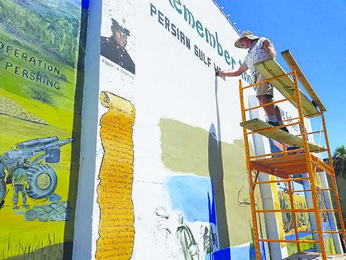 Flagler Beach artist Daniel Rose paints the heading over the Persian Gulf War section of the Veterans Memorial Mural in Palatka.