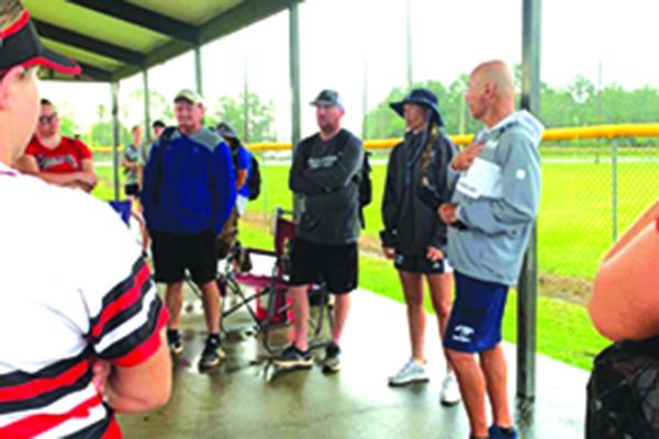 Softball coaches hang out under the pavilion at Theobold Sports Complex as rain falls Monday at the fourth annual College Softball Showcase. (Submitted photo / COREY BOOTH)